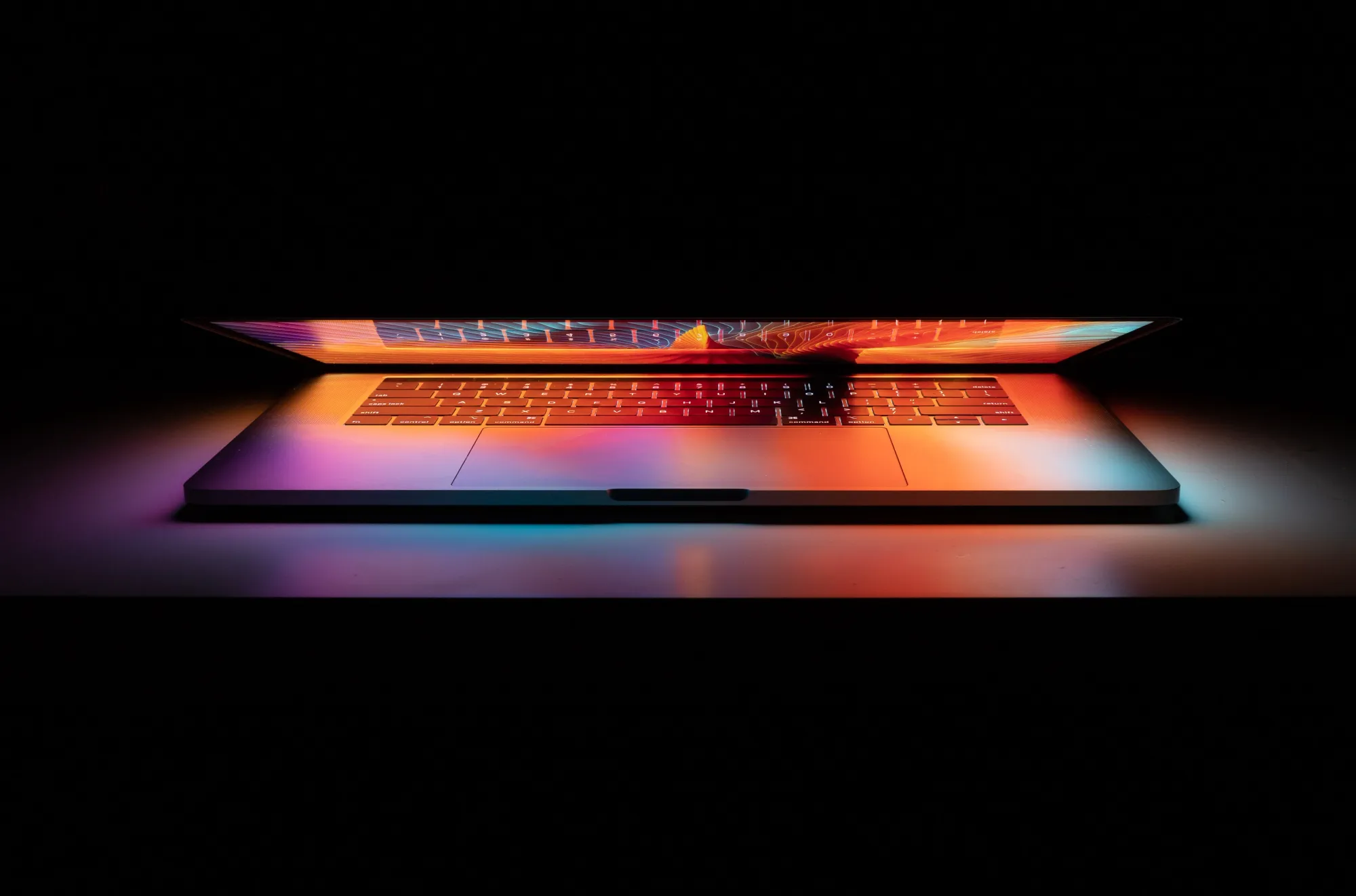 MacBook glows colorful in the darkness