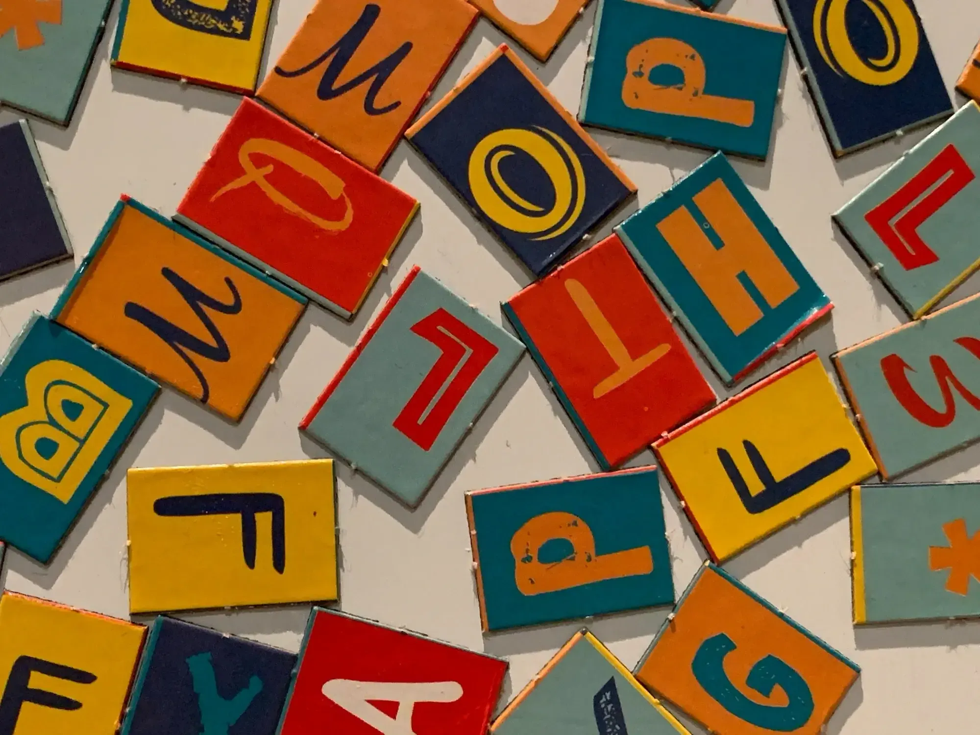Colorful plates with letters on them laying mixed together.