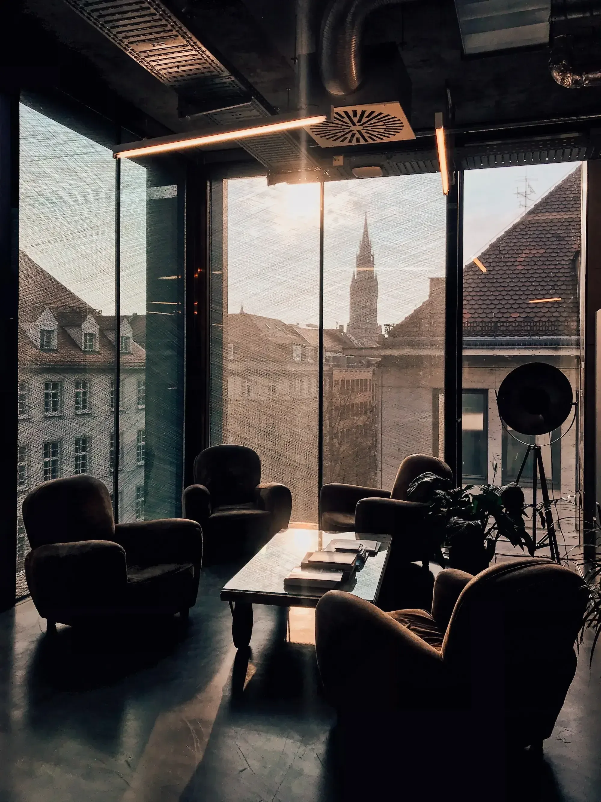 Offener und heller Büroraum mit bequemen Stühlen in einem Glasgebäude, im Hintergrund die Skyline von München.