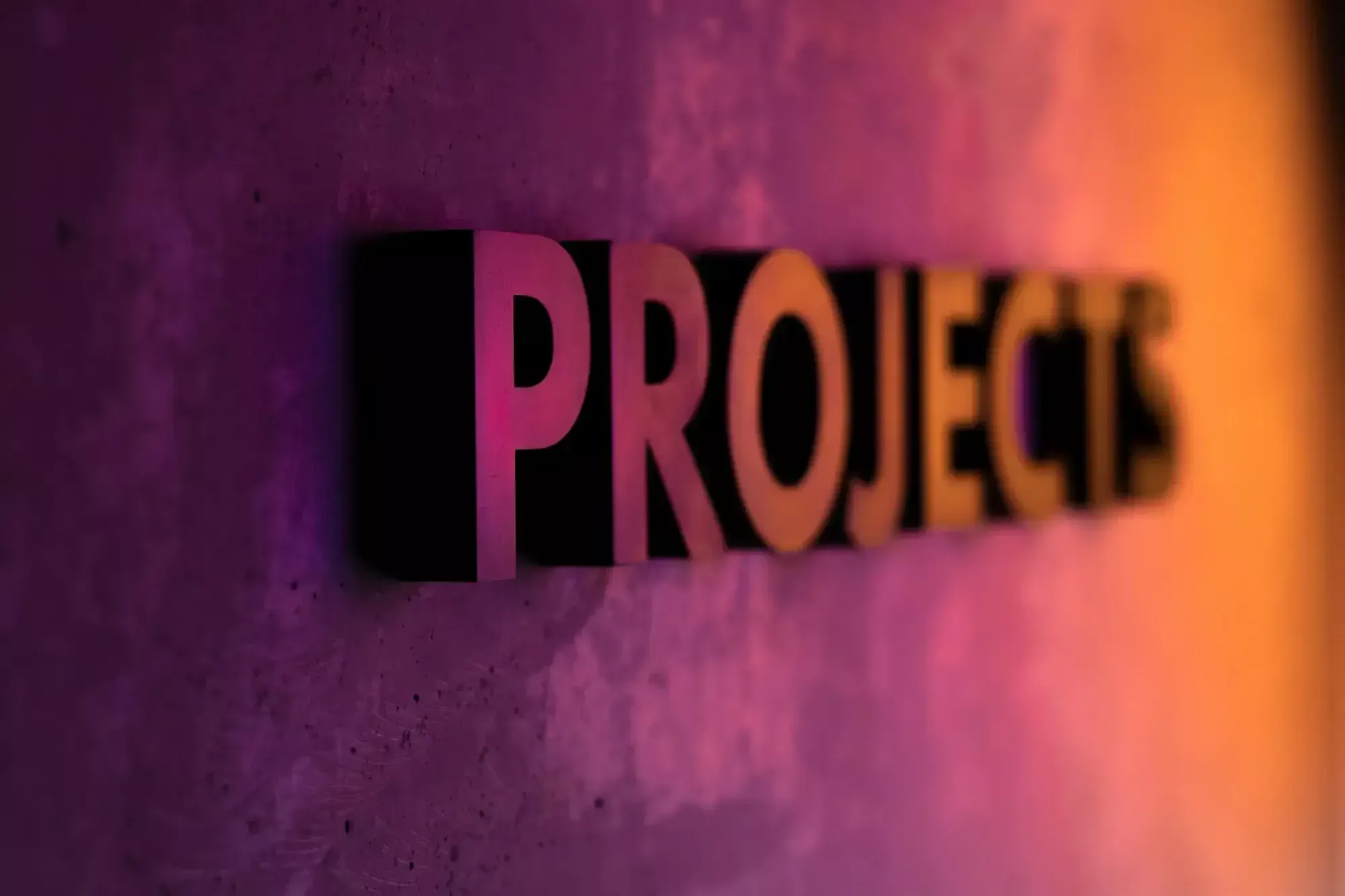 "PROJECTS" as wall decoration in pink-orange light.