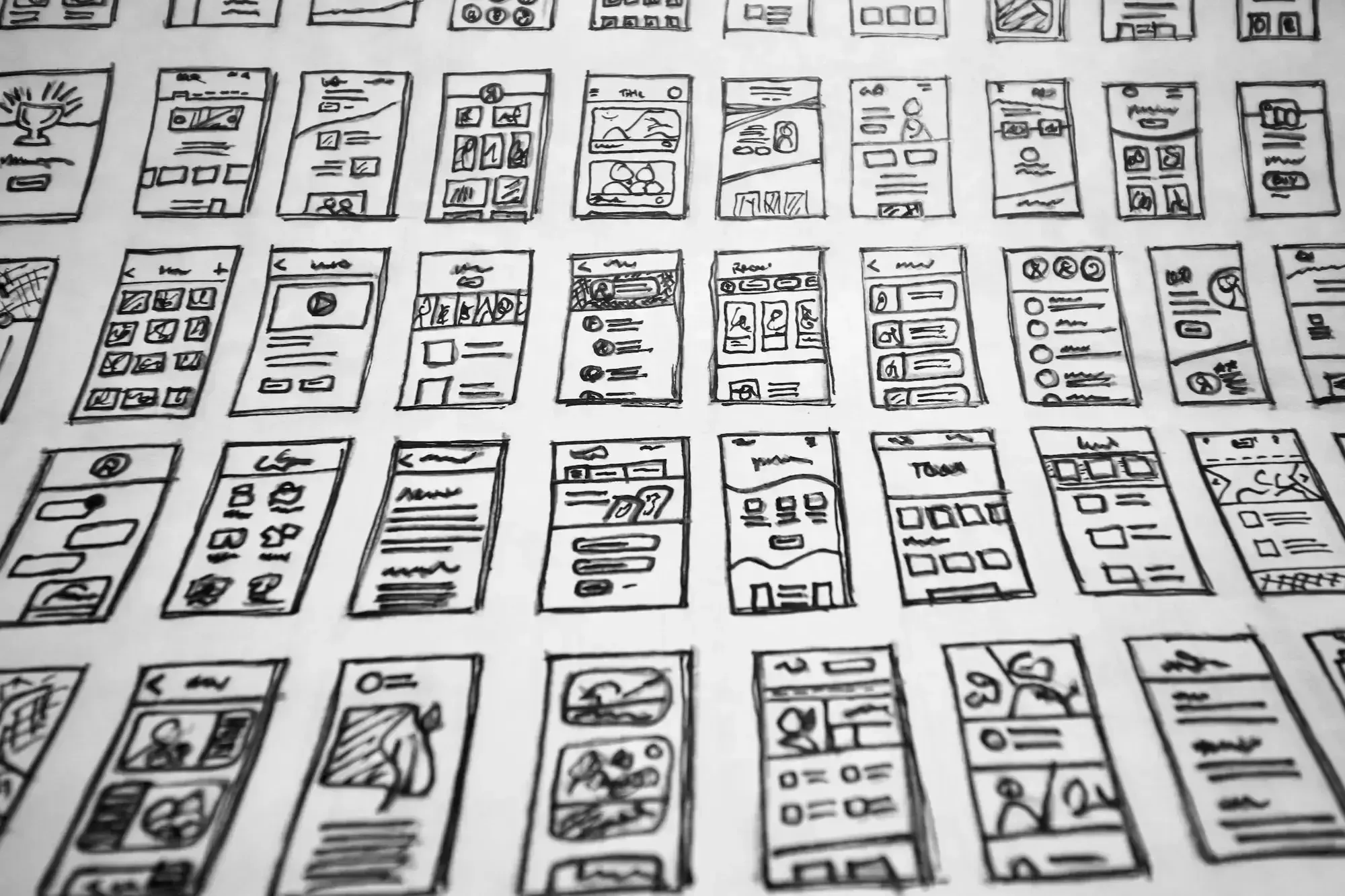 Black and white photo of several sketched screens by hand placed in rows.