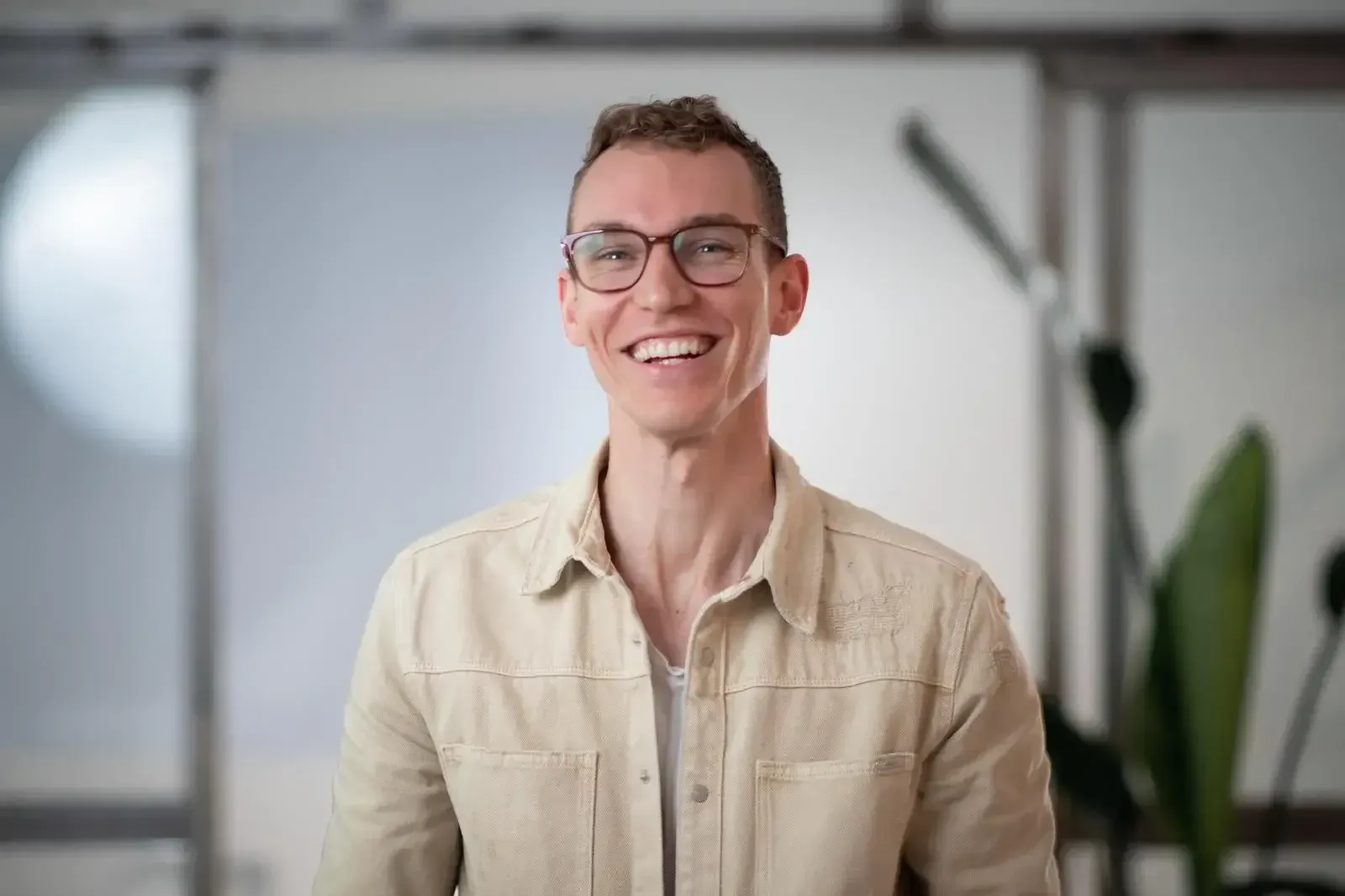 Laughing Man with glasses and a beige button down laughing into the camera