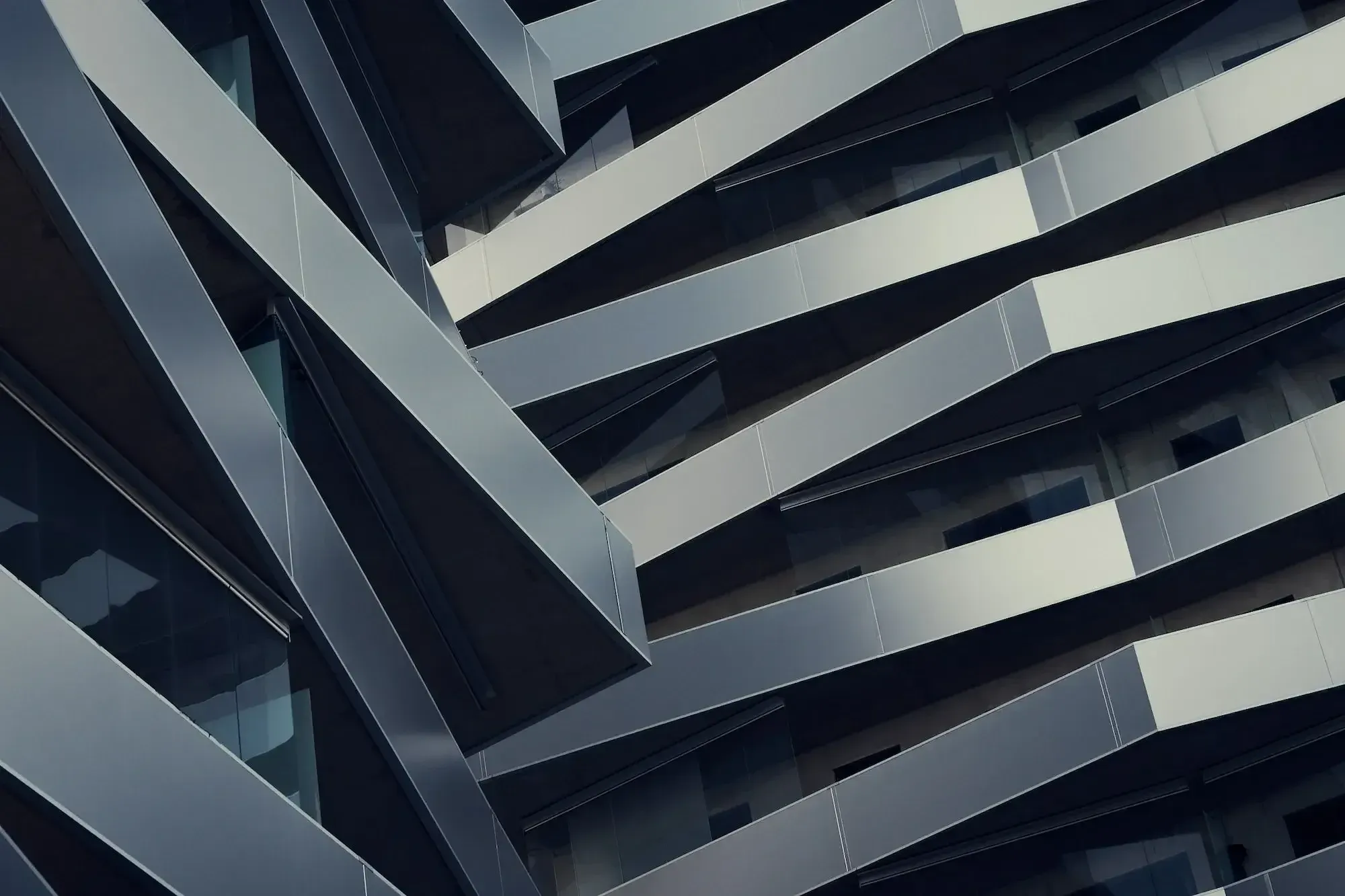 Gebäude mit grauen, polierten Elementen, die ineinandergreifen. Von unten fotografiert.
